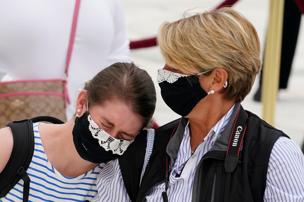 “Entonces Sandra Day O'Connor (la primera mujer elegida para la Corte Suprema) y yo pensamos que sería apropiado incluir algo típico de una mujer como parte de nuestras togas. Así que tengo muchos, muchos collares", agregó Ginsburg. En la fotografía dos mujeres lloran frente a los restos de la magistrada, llevando mascarillas para protegerse del covid-19 con referencias a su famoso collar.