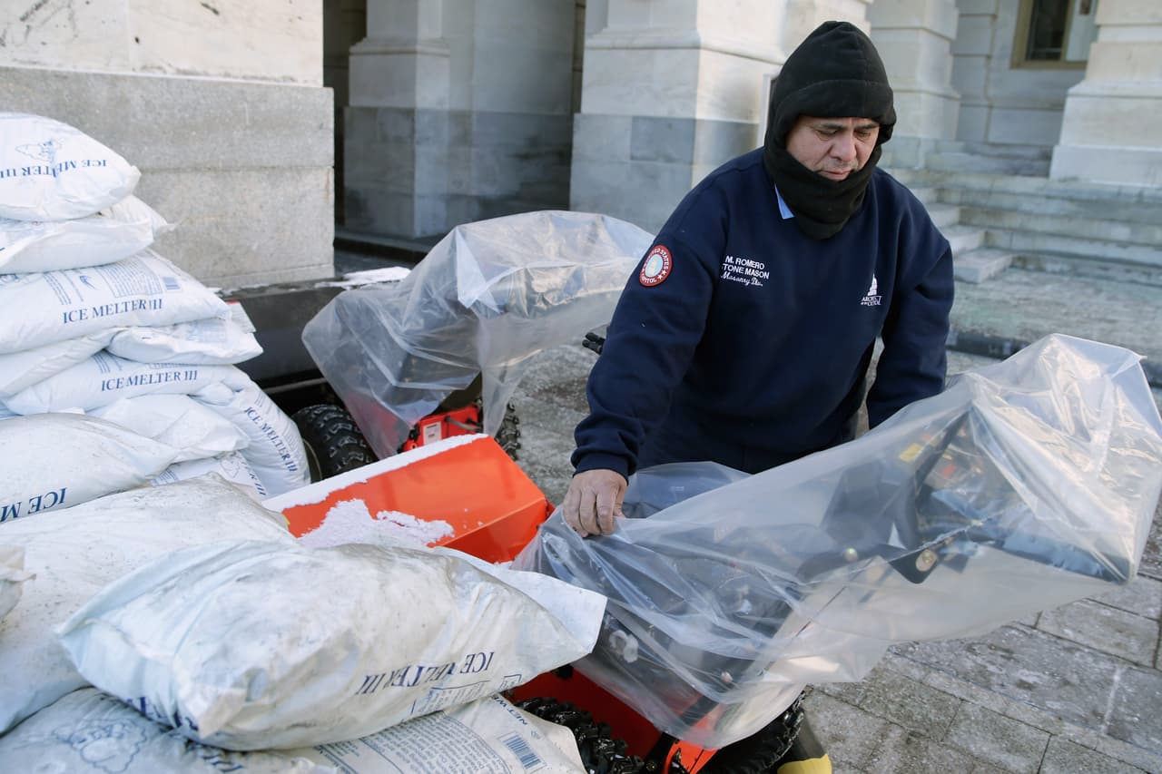 Rodeado de bolsas de sal, fusionadas con hielo, el albañil Medardo Romero cubre las barredoras de nieve con bolsas de plástico.