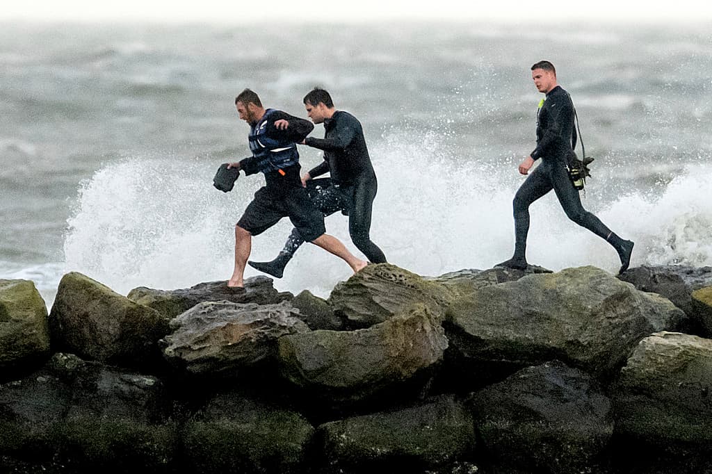 Los trabajadores de rescate ayudan a un navegante, a la izquierda, después de que su velero se desvió hacia un rompeolas mientras arrastraba su ancla el domingo 4 de febrero de 2024 en Alameda, California. Los fuertes vientos y las fuertes lluvias están afectando la región. (Foto AP/Noah Berger)