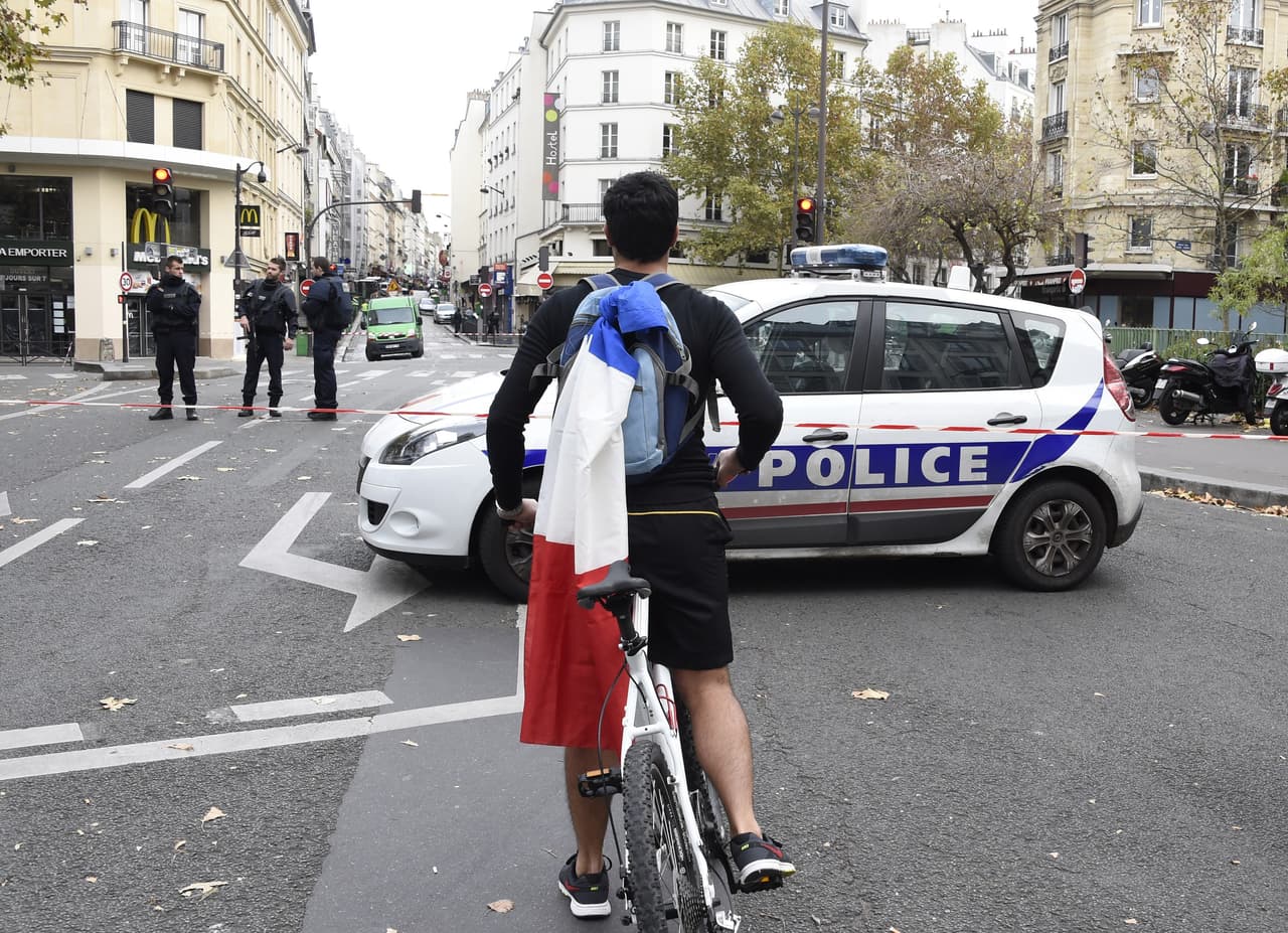 Un joven en bicicleta carga con la bandera de Francia en su espalda en el Distrito 10 zona que se mantiene acordonada.