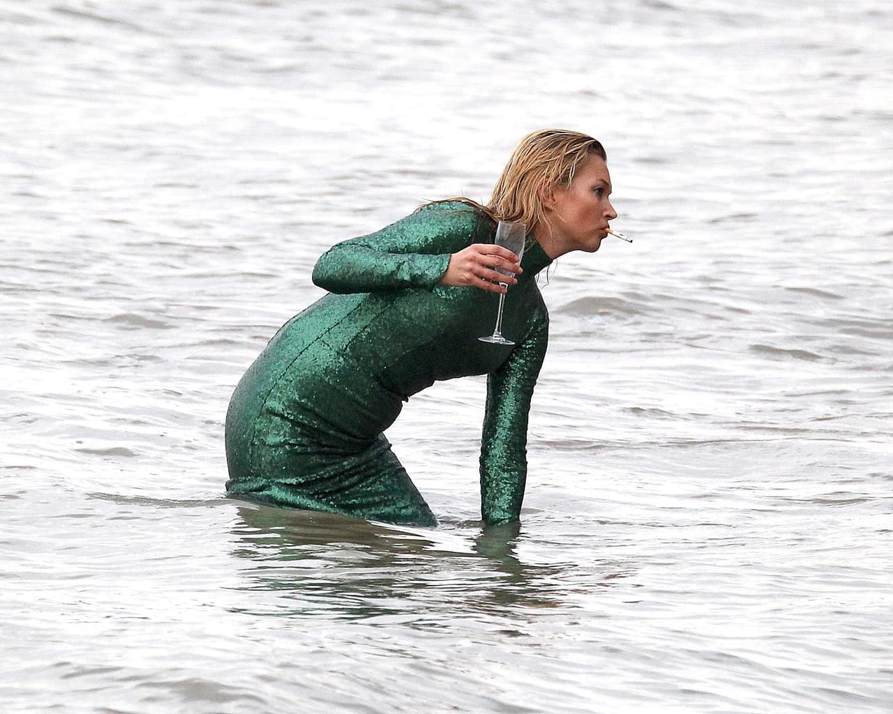 Con cigarro en boca y un vaso de champaña.