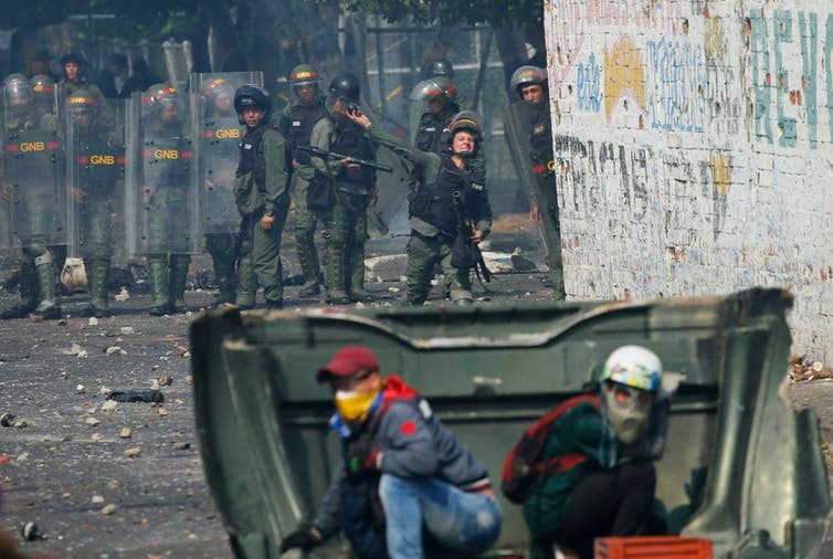 Un oficial de la Guardia Nacional de Venezuela lanza gas lacrimógeno hacia los manifestantes durante un enfrentamiento por la ayuda humanitaria en la frontera con Colombia el 23 de febrero de 2019. Cuatro manifestantes murieron.