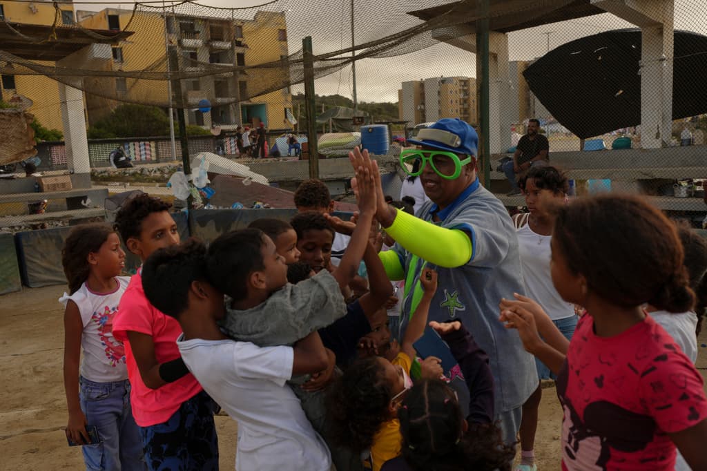 El payaso Jason Torrellas, conocido como "Jajacito", juega con niños que perdieron sus hogares tras los terremotos que azotaron Catia La Mar, Venezuela, el lunes 29 de junio de 2026. (Foto AP/Matias Delacroix)