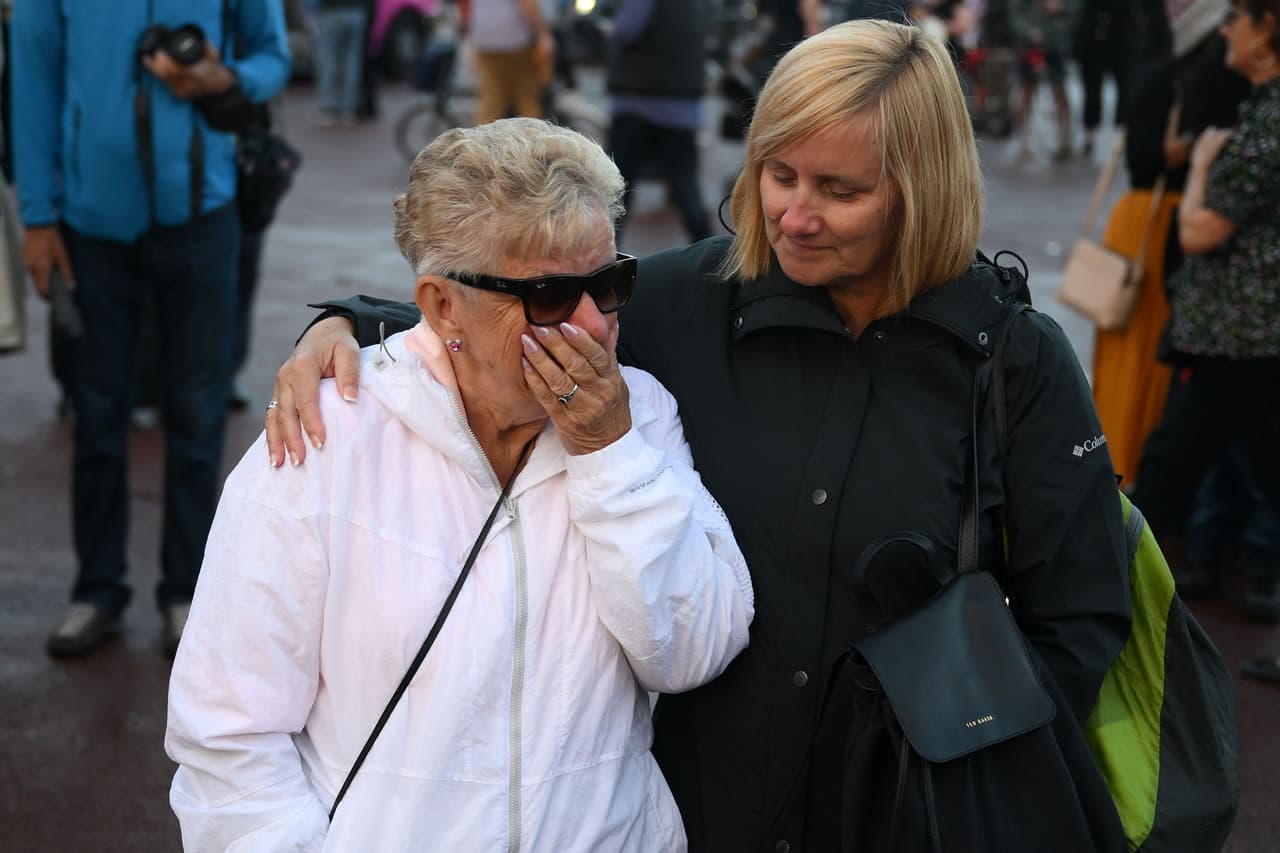 Una mujer llora y es consolada en las afueras del palacio de Buckingham tras conocerse la noticia sobre la muerte de la reina más longeva de Inglaterra.