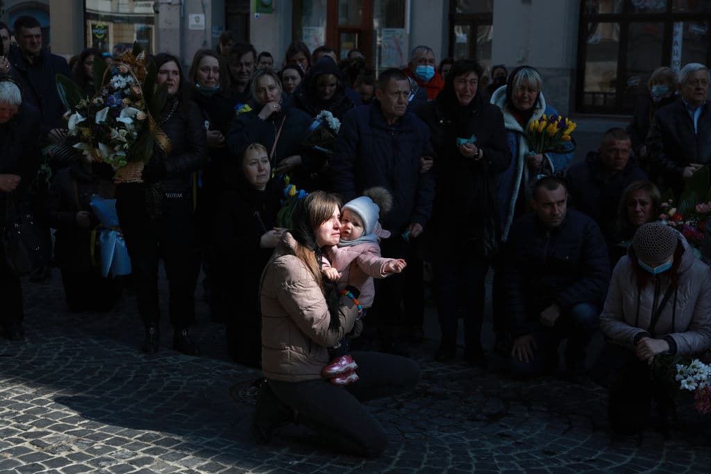 Tatiana Rurak sostiene a su hija Oleksandra Rurak mientras ve a los soldados rusos cargar el ataúd con los restos de su esposo Volodymy Rurak al interior de la Iglesia de los Santos Apóstoles Pedro y Pablo en Lviv, Ucrania, este viernes 25 de marzo de 2022.