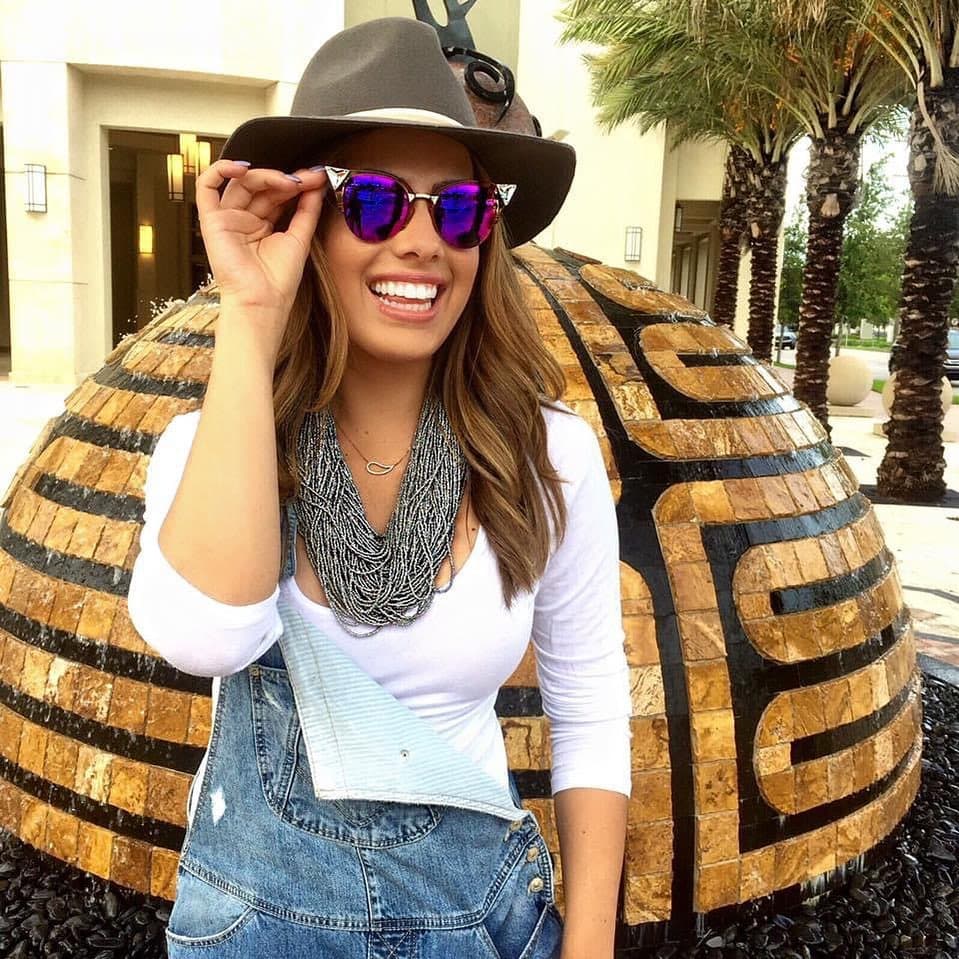 Nuestra experta en moda, Andrea Chediak no podía faltar en la lista de looks con sombreros, ella agregó unas gafas 'cat eye' con toques tornasol y metálicos y un exhuberante collar que levantó el 'overol denim'.