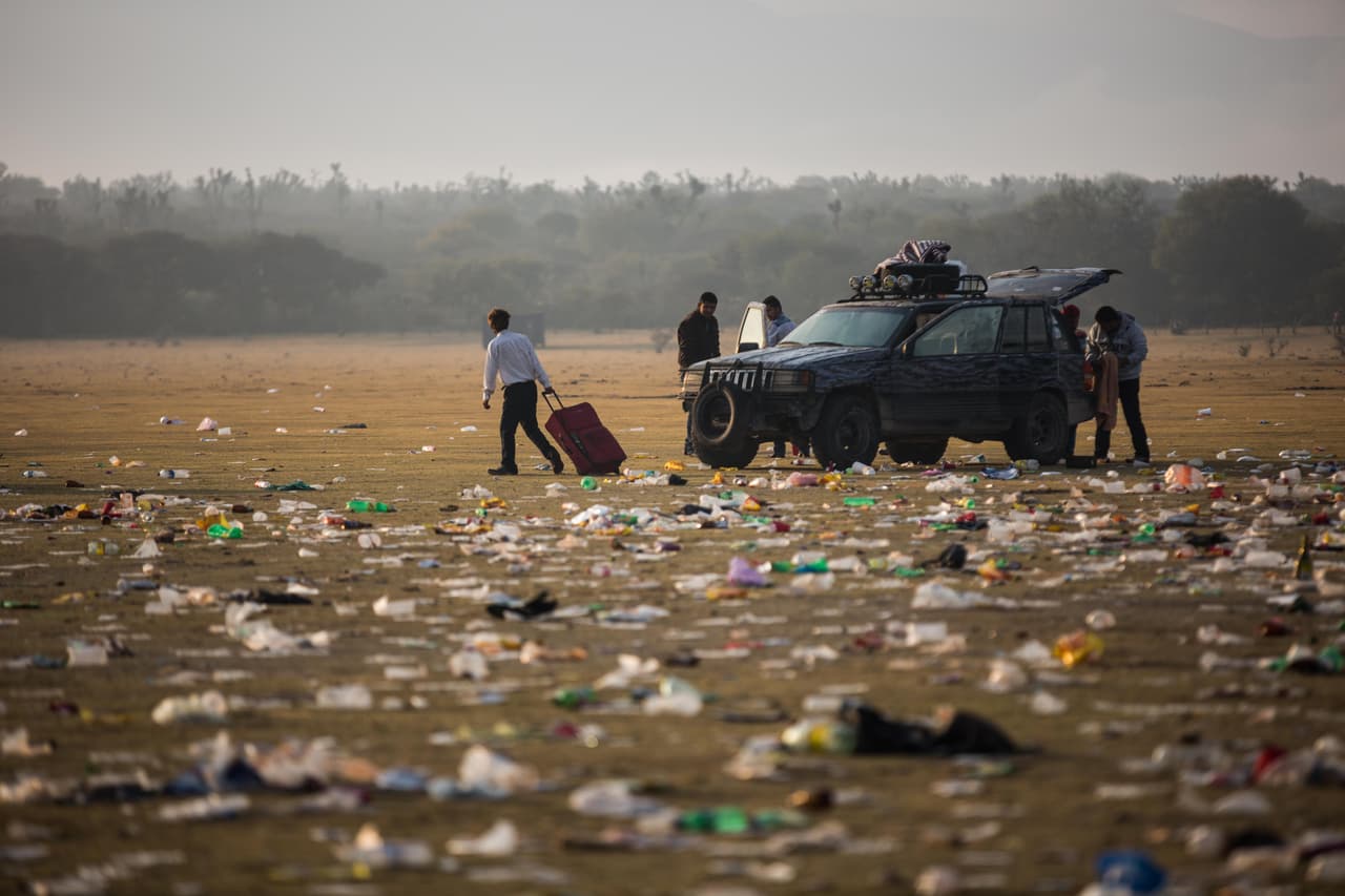Un hombre arrastra su maleta la mañana después de la fiesta a través de la explanada llena de basura donde aproximadamente 5,000 personas asistieron a los conciertos de los XV de Rubí. El municipio vuelve a la normalidad tras los festejos: escasez de combustible, acceso escaso a iluminación pública, y en zonas como La Joya, el pueblo de Rubí, falta de acceso a señal celular e internet.
<i>Almudena Toral</i>