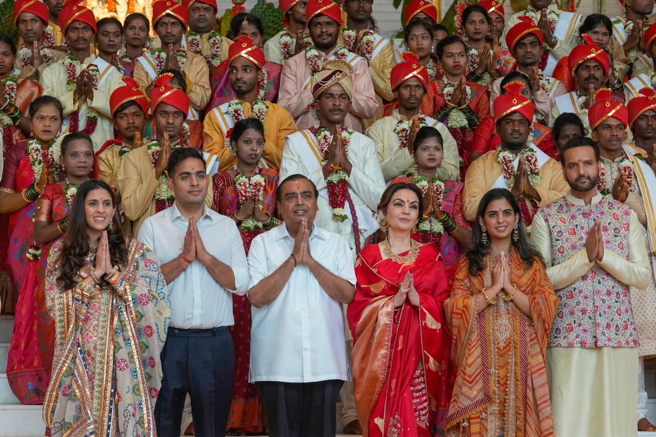 Chairman of Reliance Industries Limited Mukesh Ambani, third from left, poses for a photograph with his family members and underprivileged couples during a mass wedding organized by him as the part of pre-wedding celebrations of his youngest son, Anant Ambani, in Navi Mumbai, India, Tuesday, July 2, 2024. (AP Photo/Rafiq Maqbool)