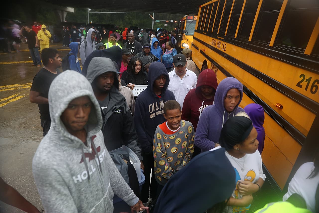 Afectados por las inundaciones esperan para abordar los autobuses que ayudan a evacuar la ciudad de Houston.