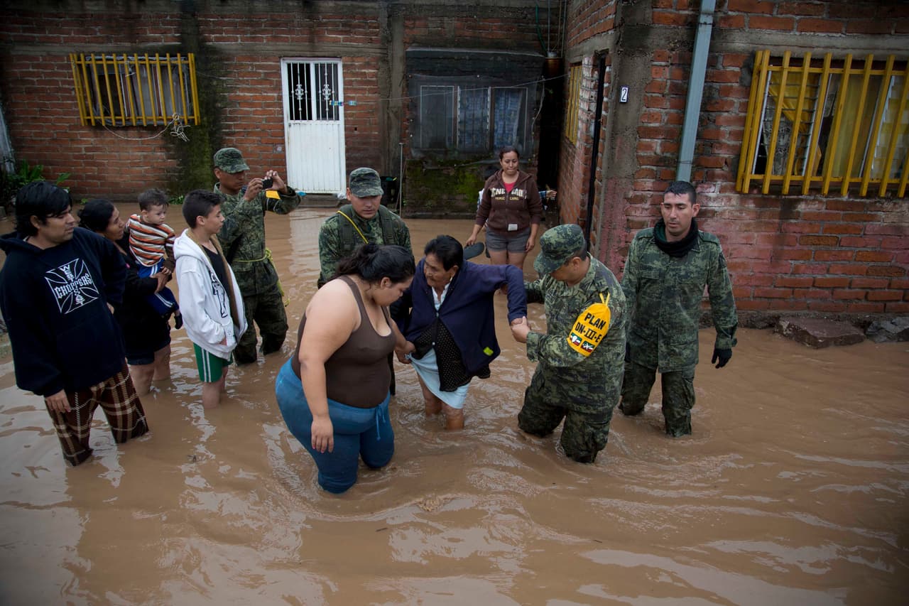 Unos soldados ayudan a una mujer a salir de su casa en un área inundada de Zoatlán, Nayarit.