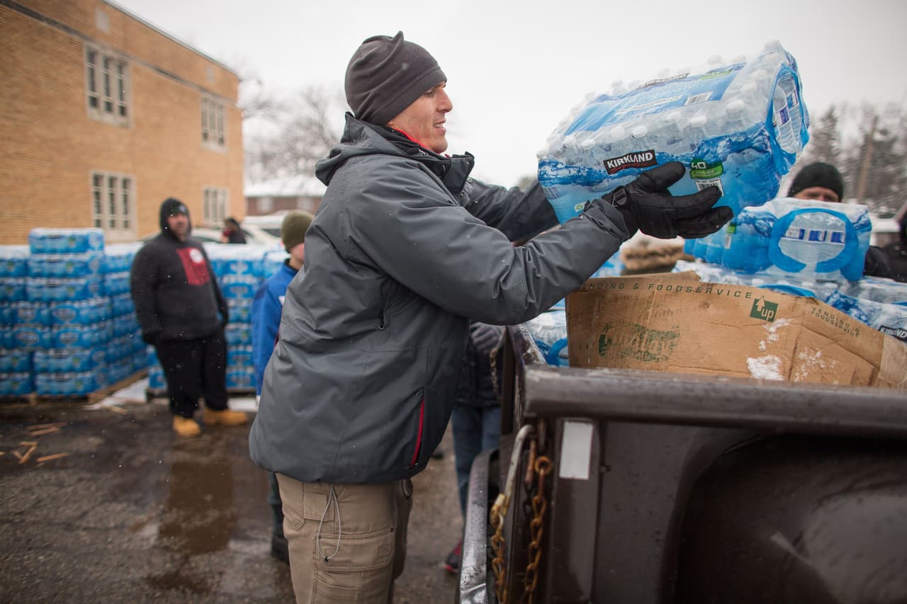 Voluntarios cargan cajas de agua a unos autos esperando en Salem Lutheran Church en Flint, Michigan el 5 de Marzo, 2016.