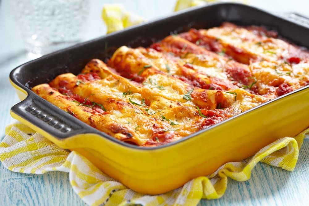 Enchiladas de Pollo. Simplemente deliciosas, este plato se hace solo con una tortilla de maíz común y corriente rellena de una salsa de tomate con chile y pollo mechado. Pero ahora debes meterlas al horno en vez de usar sartén y gratinar con salsa de tomate y mucho queso. ¡No te puedes resistir!