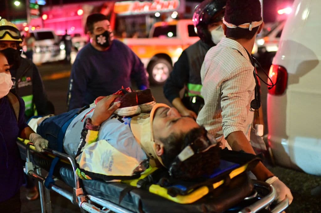 Emergency workers carry an injured person away on a stretcher after an overpass for a metro partially collapsed in Mexico City on May 3, 2021. - At least 15 people were killed and dozens injured as an elevated metro line collapsed in the Mexican capital on May 3 as a train was passing, authorities said. (Photo by Pedro PARDO / AFP) (Photo by PEDRO PARDO/AFP via Getty Images)