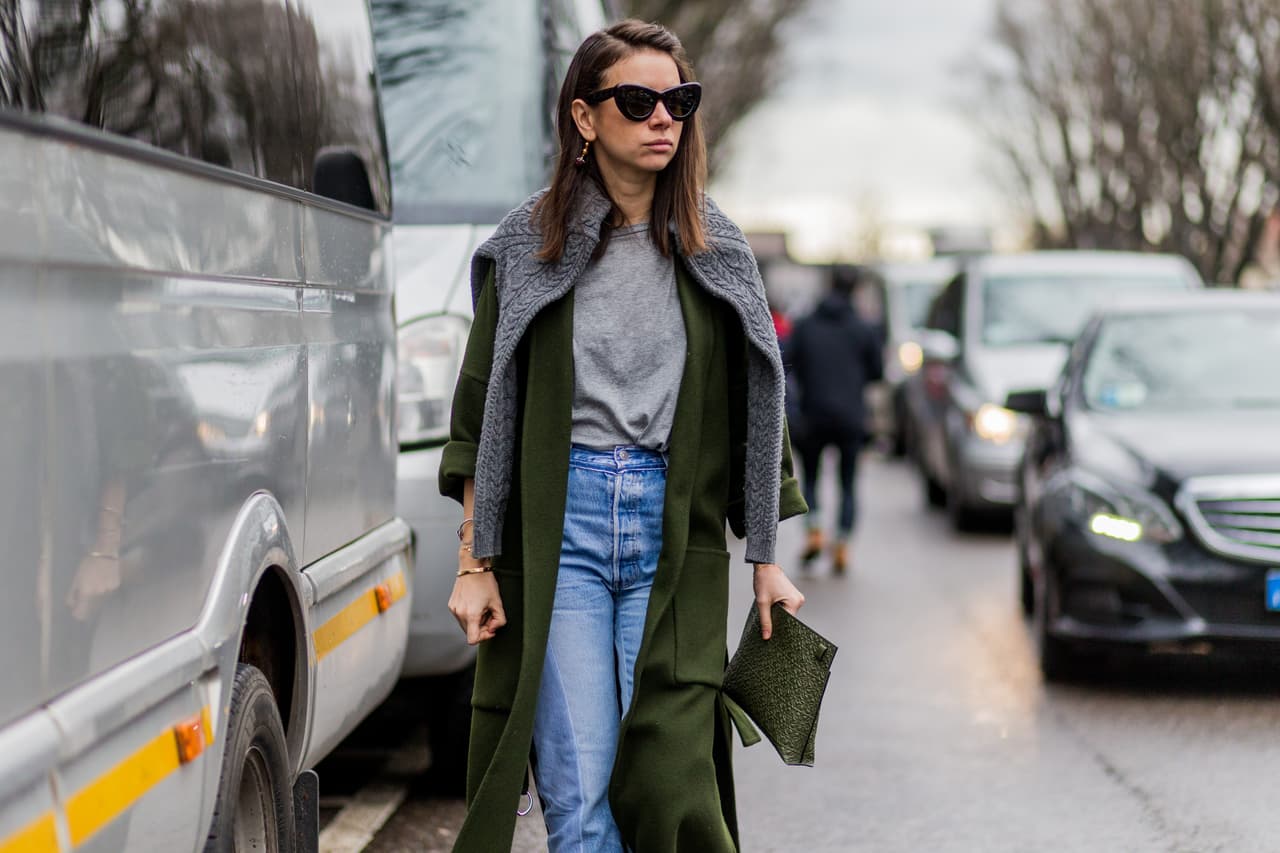 Una t-shirt gris es un básico que nunca sobra. Apúntala en la lista de número uno si aún no la tienes. Esta glamurosa paseante de París la eligió como la base de un atuendo de jeans y abrigo paño verde militar.