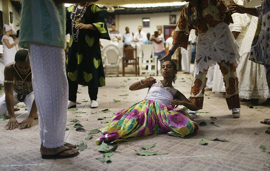 ITABORAI, BRAZIL - JANUARY 24: A worshipper (C) is overcome during a Candomble ceremony on January 24, 2016 in Itaborai, Brazil. Candomble is an Afro-Brazilian religion whose practitioners sometimes fall into trances during ceremonies believing they have become possessed by gods, or orixas. The roots of the Candomble religion came to Brazil via African slaves and eventually incorporated some elements of Catholicism. Some believers have faced persecution in Brazil and ceremonies are often conducted privately. (Photo by Mario Tama/Getty Images)