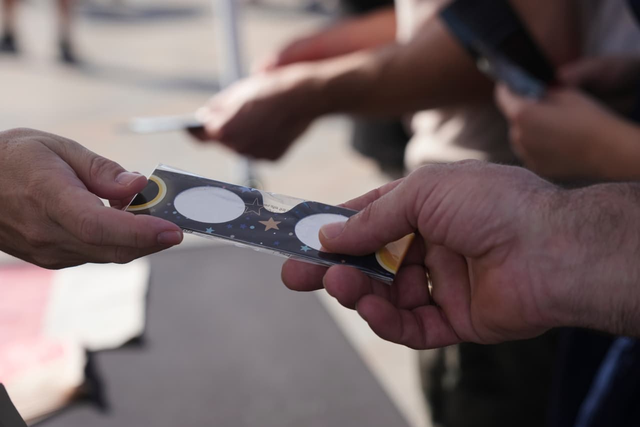 Unas personas intercambian gafas especiales para eclipses antes de un eclipse solar total que comenzará cerca del atardecer, en una playa cercana a Valencia, España, el miércoles 12 de agosto de 2026.