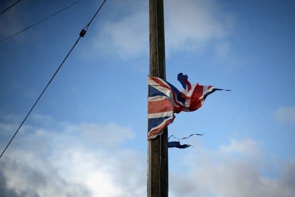 Una bandera de Gran Bretaña está atrapada en torno a un poste de luz fuera de un hogar inundado.