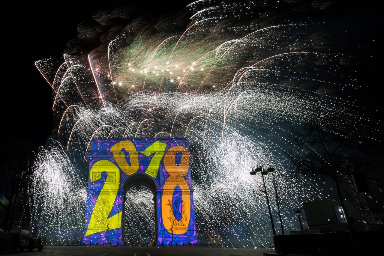 El Arco del Trifuno, en París, da la bienvenida al 2018 mientras en el fondo estallan miles de luces artificiales.