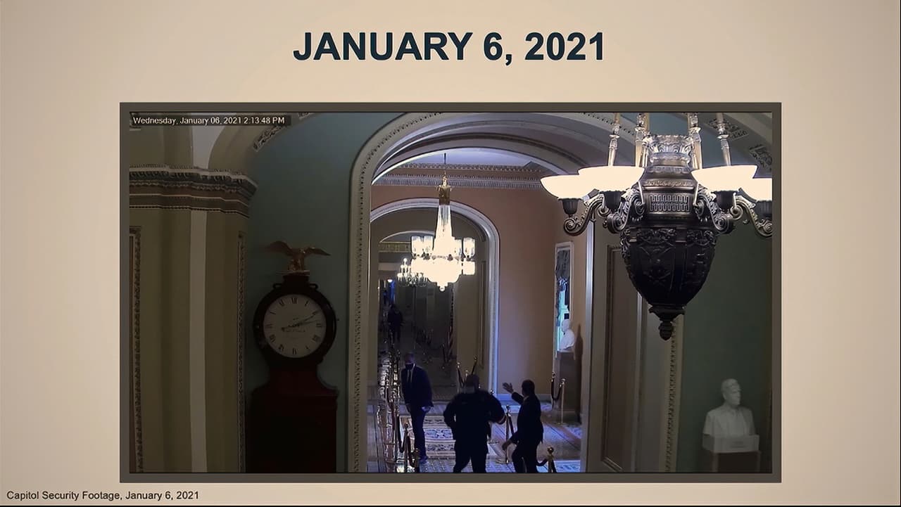 En esta imagen del video, un video de seguridad muestra al oficial de policía del Capitolio de los EE. UU. Eugene Goodman pasando al lado del senador Mitt Romney.