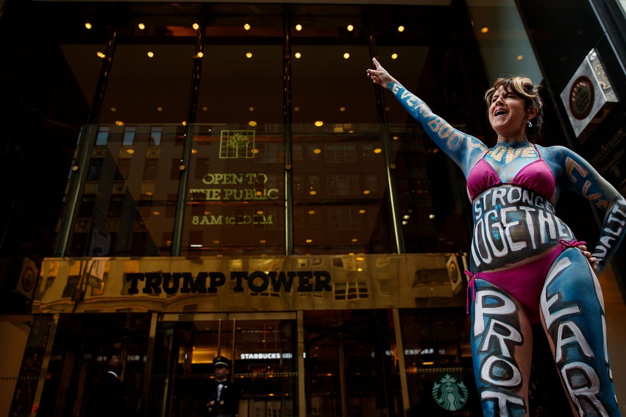 "Juntos somos más fuertes", lema de campaña de la derrotada demócrata Hillary Clinton, fue el mensaje que Gigi Love lució este lunes en la parte frontal de su cuerpo durante su manifestación frente a la Torre Trump, en Manhattan.