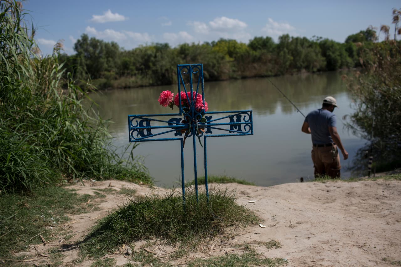 Un hombre pesca en el Río Bravo, junto a una cruz colocada en memoria de un migrante que murió del lado mexicano del rio, antes de llegar a Estados Unidos. 25 de marzo de 2017.