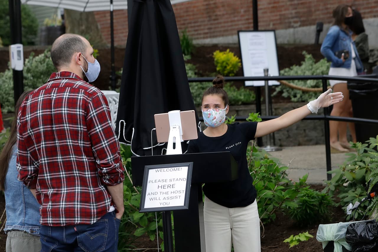 La anfitriona de un restaurante en Barrington, Rhode Island, recibe a los clientes que llegan al local reabierto el 18 de mayo. Este estado permitió la atención de clientes en los espacios al aire libre.