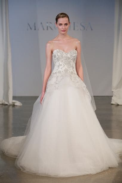 En su primera boda, la 'celebrity' usó un vestido de falda amplia de tul en color blanco puro, sin embargo parece que Kim se decantará por algo diferente. Este modelo de la firma Marchesa tiene aplicaciones de pedrería y falda amplia de tul.