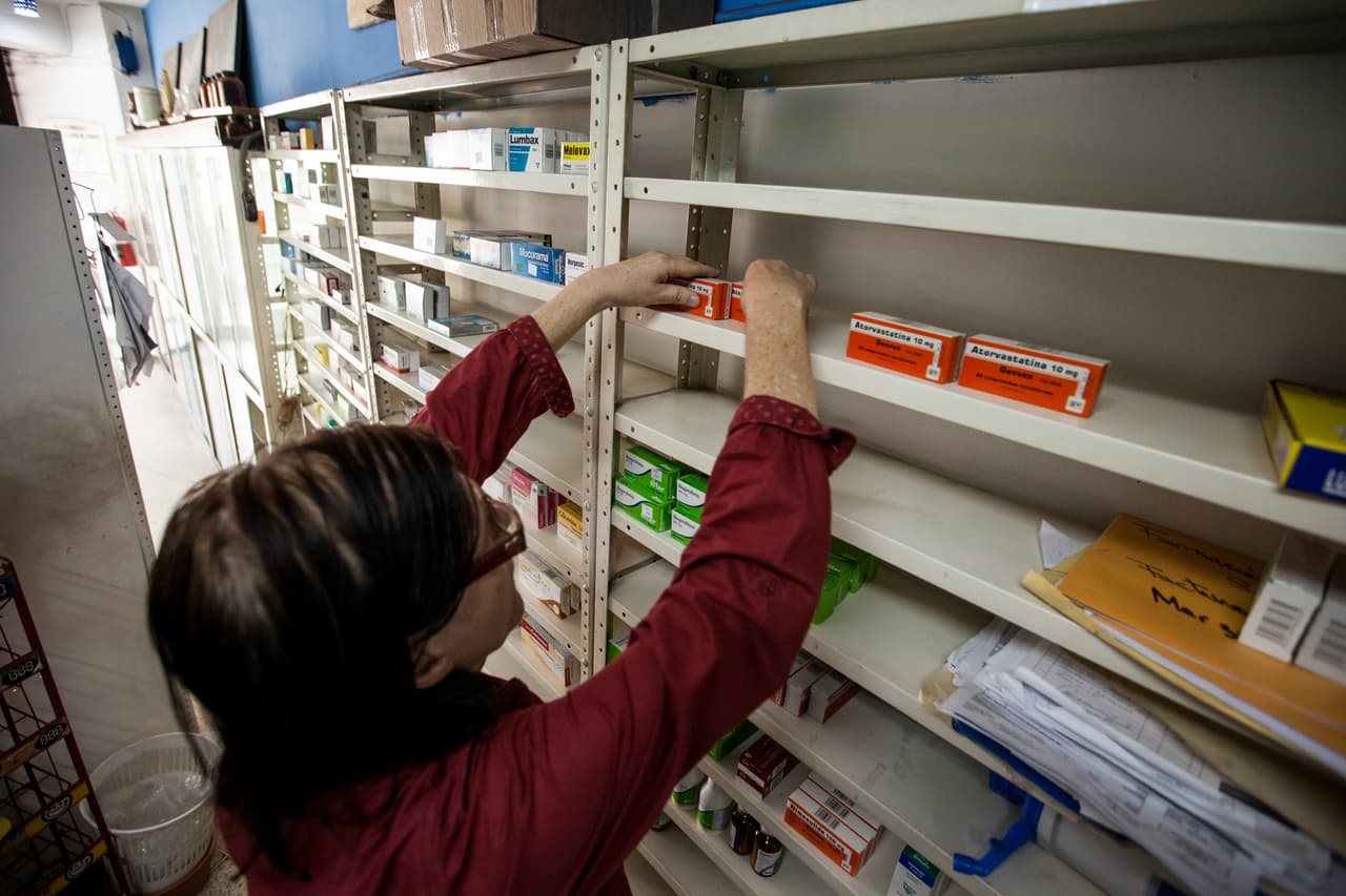 Una encargada de la farmacia "San Vicente" en Caracas arregla los pocos medicamentos disponibles en un estante