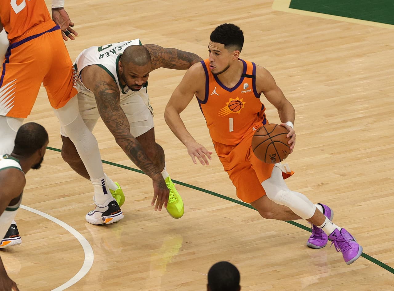 Devin Booker # 1 de los Phoenix Suns impulsa contra P.J. Tucker # 17 de los Milwaukee Bucks durante el primer cuarto del Juego Cuatro de las Finales de la NBA.