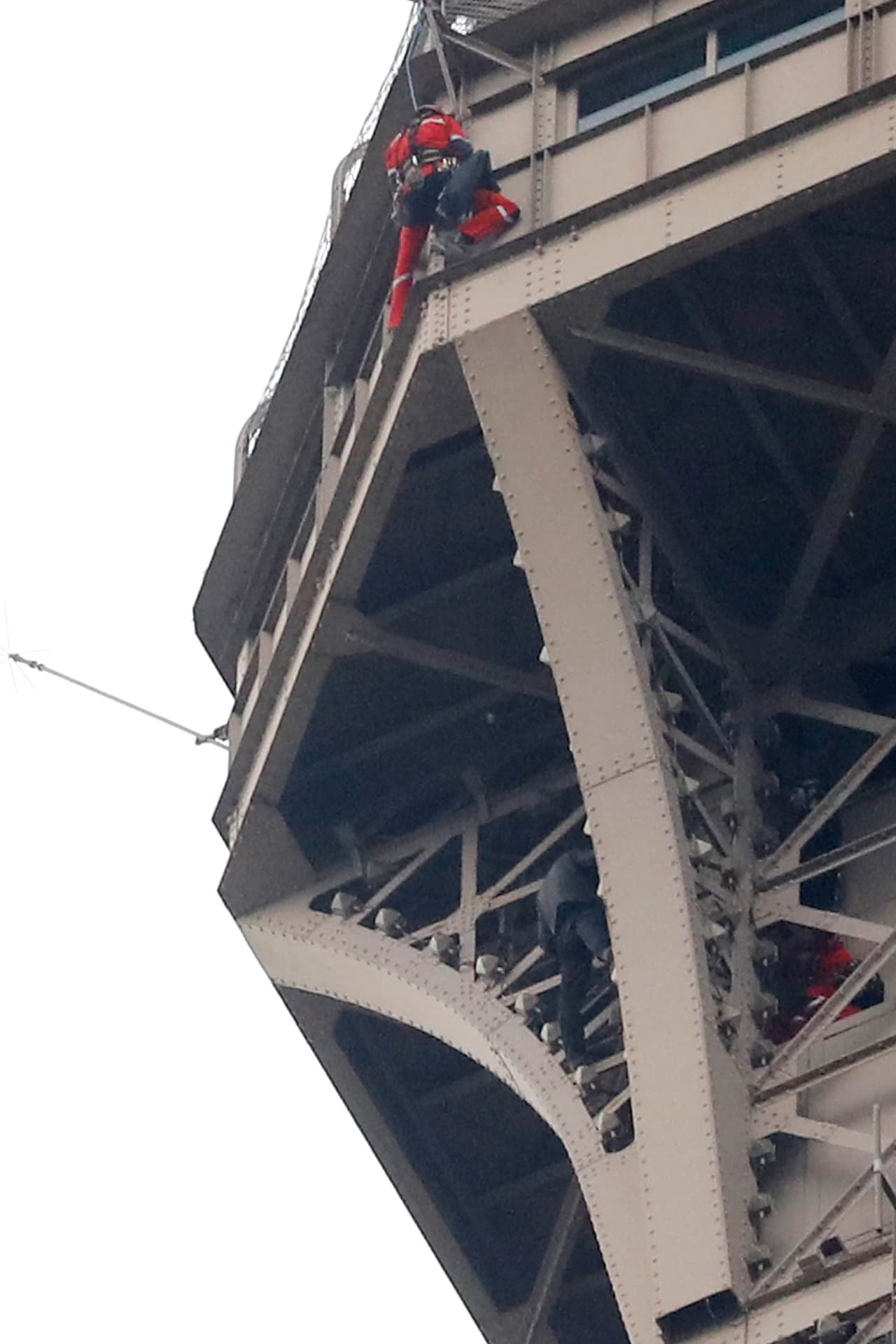 Dos rescatistas, vestidos de rojo, intentan acercarse al escalador, abajo y al centro en la fotografía.