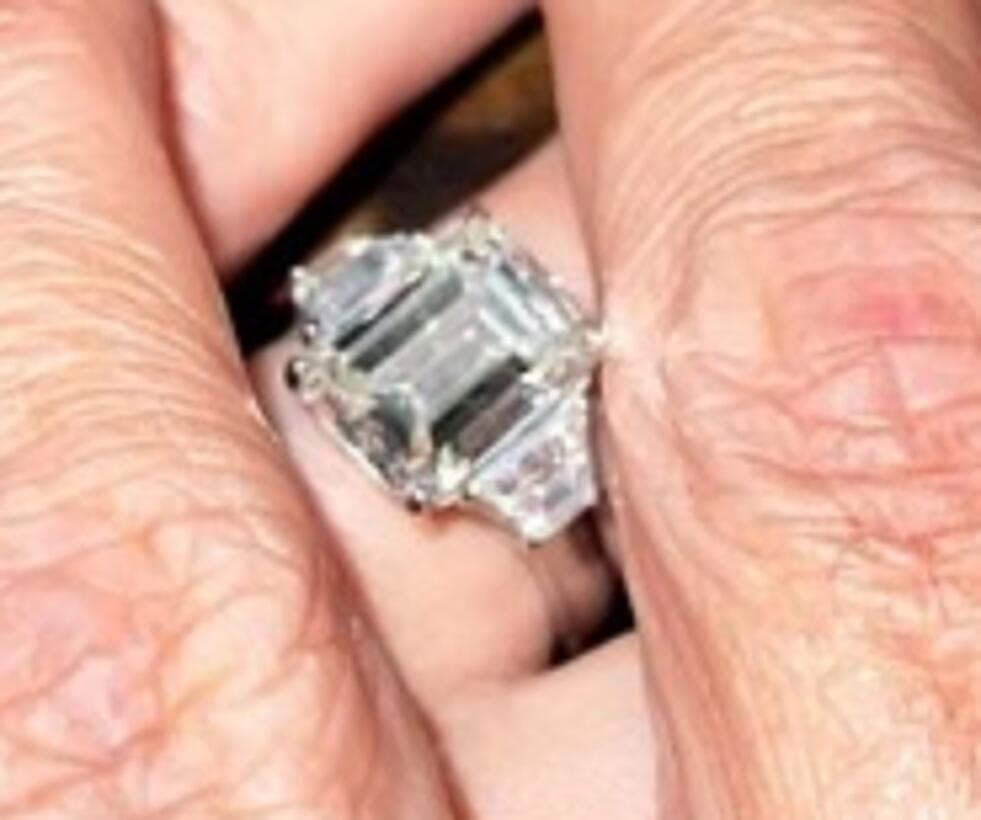 La argolla presenta dos piedras baguette cónicas colocadas a los lados de un diamante de talla esmeralda.