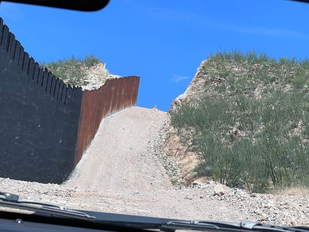 "La frontera no está abierta" dijo Jesús Vasavilbaso, vocero de la Patrulla, mientras manejaba por un camino paralelo al muro fronterizo. Al fondo de observa como partieron la montaña para construir esta carretera de terracería.