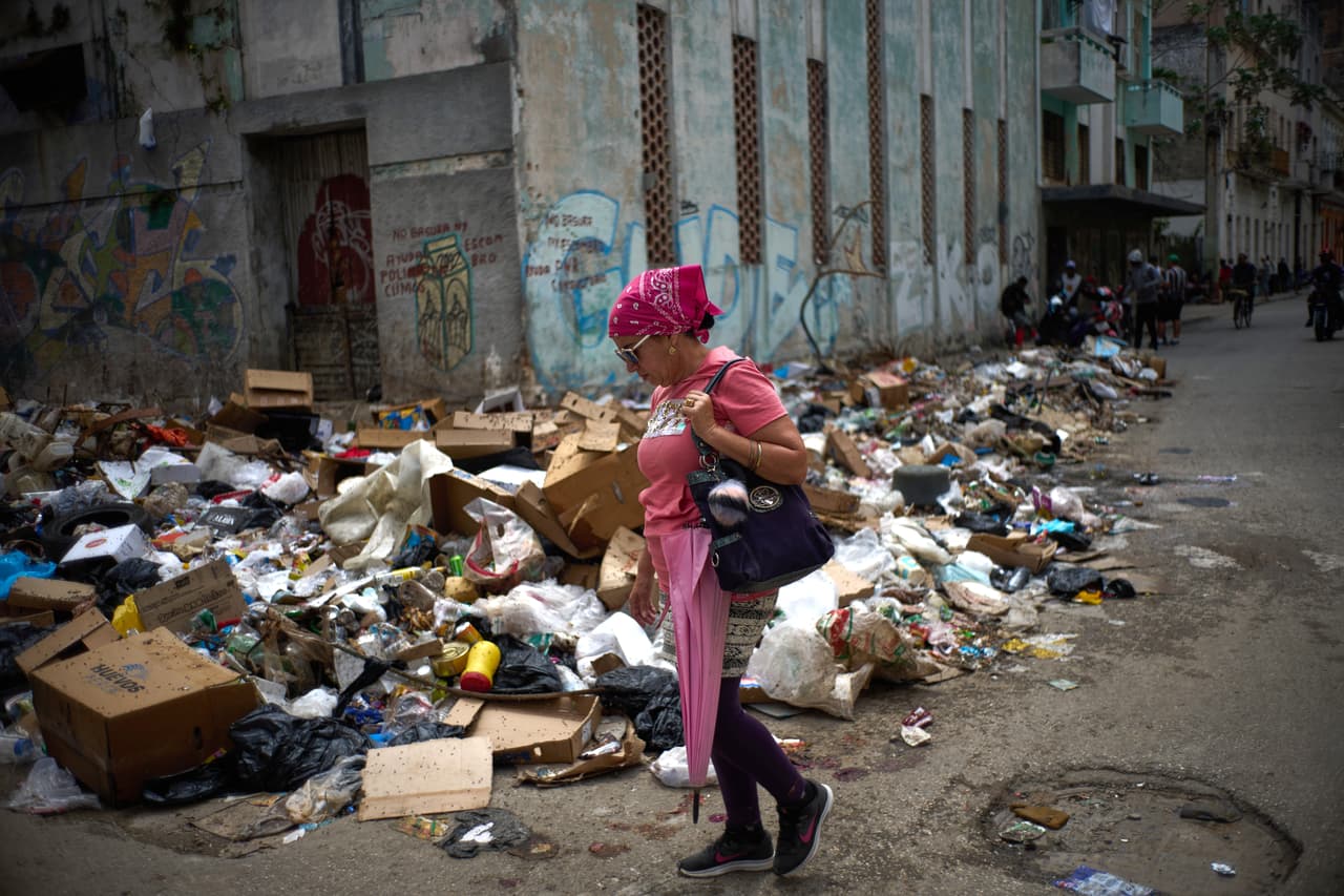 Una mujer camina por una calle junto a montones de basura en La Habana, Cuba, el jueves 19 de marzo de 2026. (Foto AP/Ramon Espinosa)