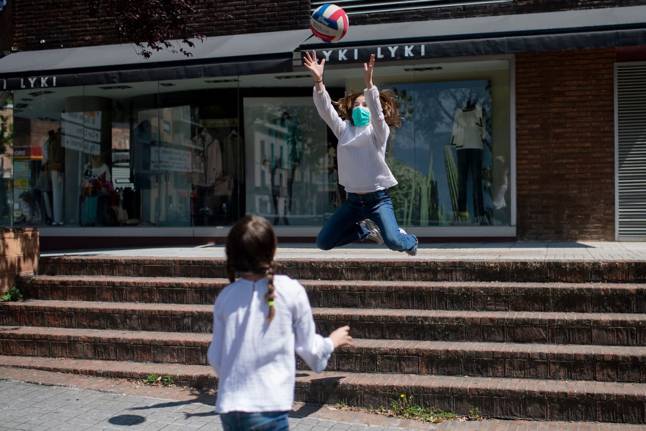 <b>A la calle después de seis semanas.</b> Dos niñas juegan protegidas con máscaras en una calle de Barcelona, el 26 de abril. Después de 45 días encerrados en casa, a los niños de España se les permite salir a jugar, uno de los primeros cambios en las estrictas normas de aislamiento en uno de los países más afectado por el covid-19