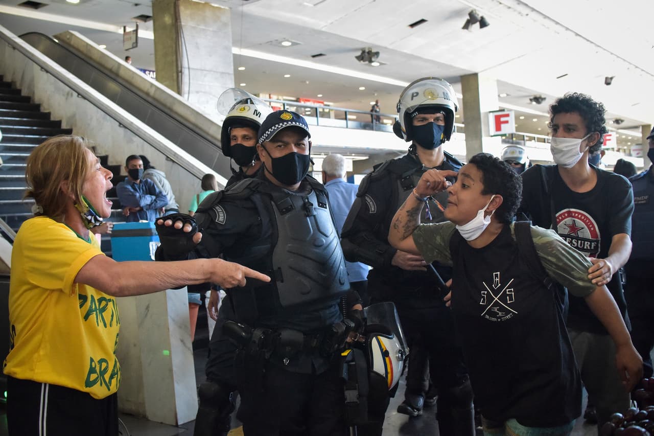Oficiales de la policía militar brasileña separan a los manifestantes leales al presidente de Brasil, Jair Bolsonaro, y a los manifestantes antigubernamentales, justo después de una protesta contra el racismo, las políticas del gobierno del presidente Bolsonaro y la defensa de la democracia en medio de la nueva pandemia del coronavirus en la Explanada de los Ministerios, en Brasilia, Brasil, el domingo 21 de junio de 2020. (Foto AP/Andre Borges)