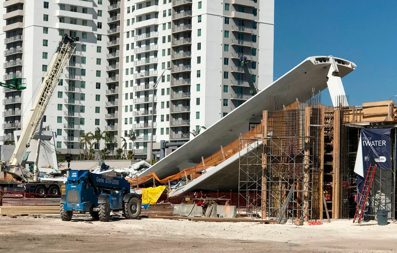 A crane is seen near a newly installed pedestrian bridge, that collapsed, over a six-lane highway in Miami, Florida on March 15, 2018, crushing a number of cars below and reportedly leaving several people dead. The Miami Herald reported that an unknown number of people were trapped underneath the collapsed walkway, which connected Florida International University to a student housing area and was erected less than a week ago. / AFP PHOTO / AFP TV / Antoni BELCHI (Photo credit should read ANTONI BELCHI/AFP/Getty Images)