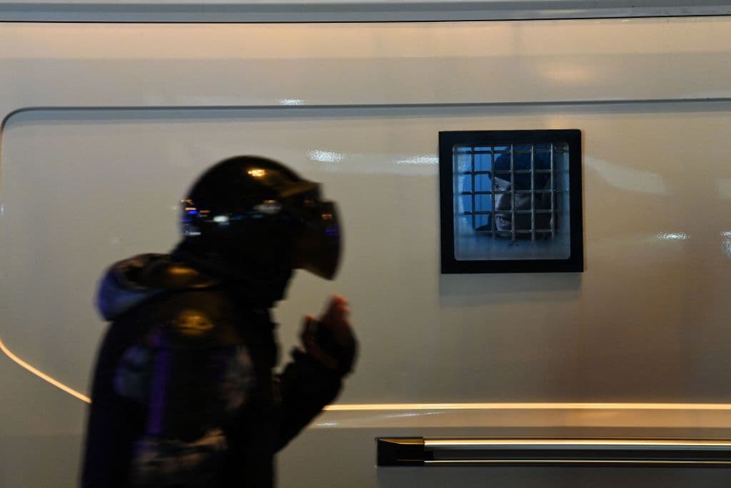 A través de la ventana de ese camión de policía se ve a una de las cientos de personas que fueron arrestadas este jueves.