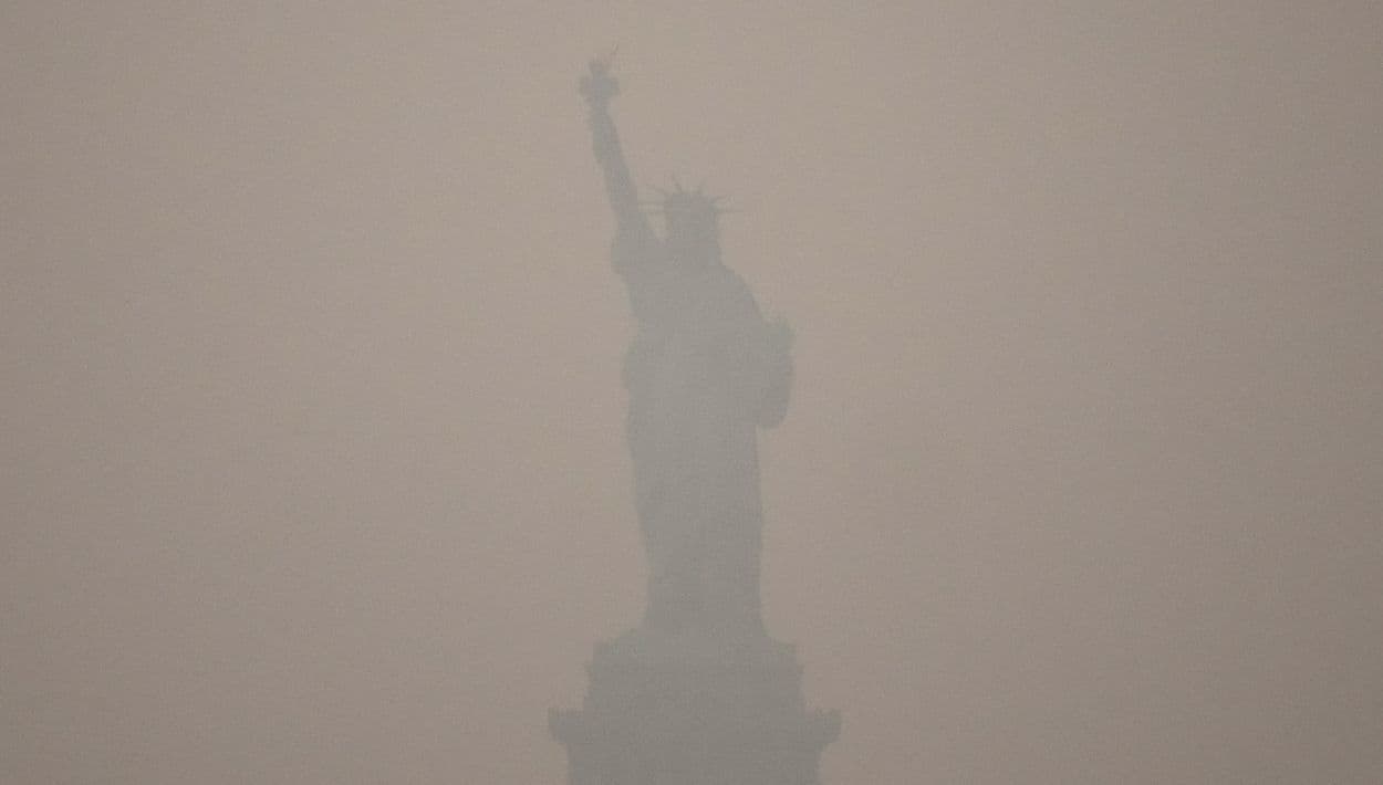 La Estatua de la Libertad se alza durante el atardecer mientras el humo de los incendios forestales cubre el cielo, el jueves 16 de julio de 2026, en el distrito de Brooklyn, Nueva York.
<br>