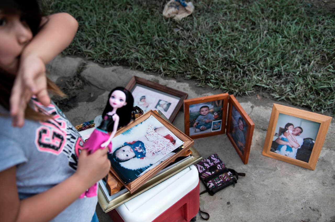Una niña organiza juguetes y fotos familiares fuera de su casa inundada. Houston, Texas.
