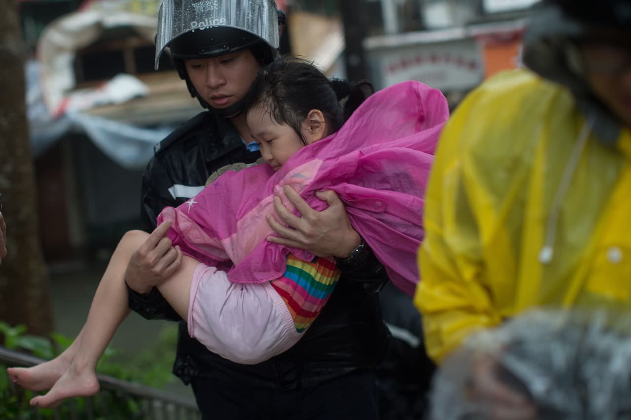 Hong Kong, China. Un policía traslada a una niña en un área inundada en Lei Yu Mun. La mayoría de las tiendas y servicios públicos se cerraron y se cancelaron más de 800 vuelos en el Aeropuerto Internacional de Hong Kong, que afectaron a más de 100,000 pasajeros.