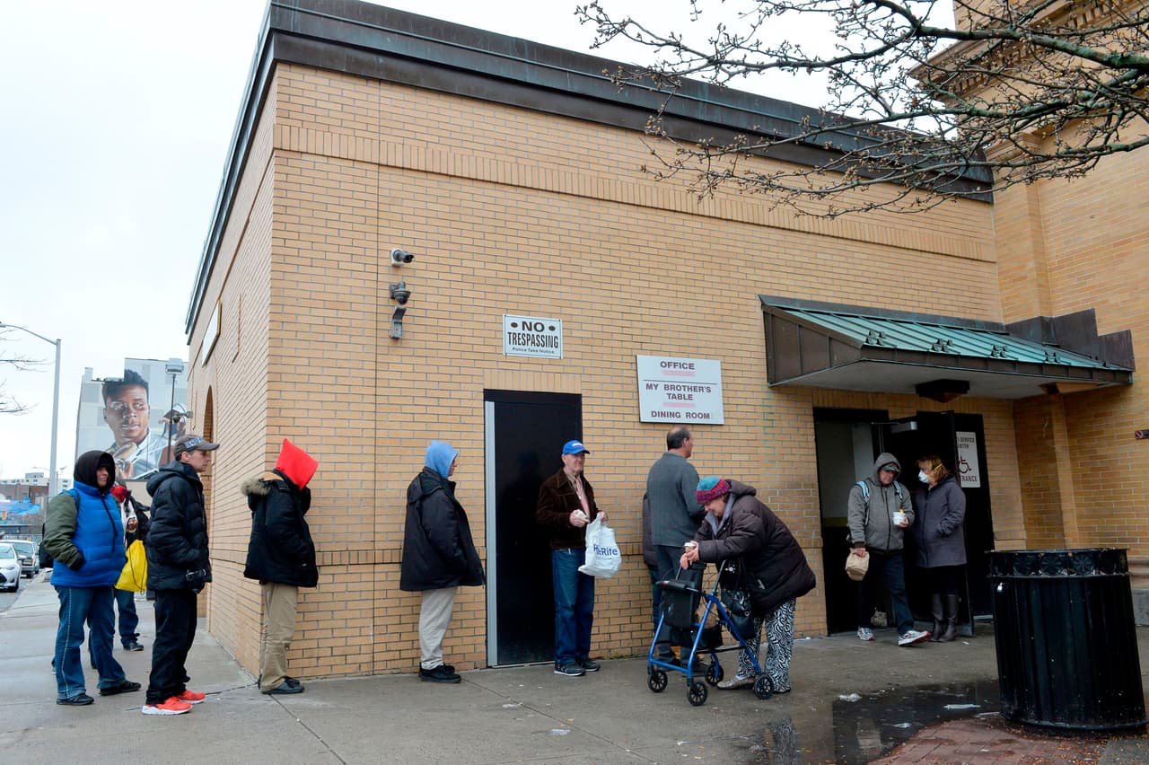 <b>Abierto a pesar del coronavirus.</b> Los asistentes al comedor comunitario de My Brother's Table en Lynn, Massachusetts, hacen fila para para almorzar, el 30 de marzo. Este establecimiento sirve un promedio de 600 comidas al día a personas sin hogar y se mantiene en servicio cumpliendo las normas de distanciamiento social.