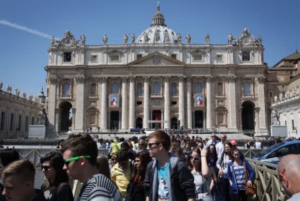 Turistas caminan frente a la Basilica de San Pedro mientras el Vaticano se alista para la canonizacion de los papas.