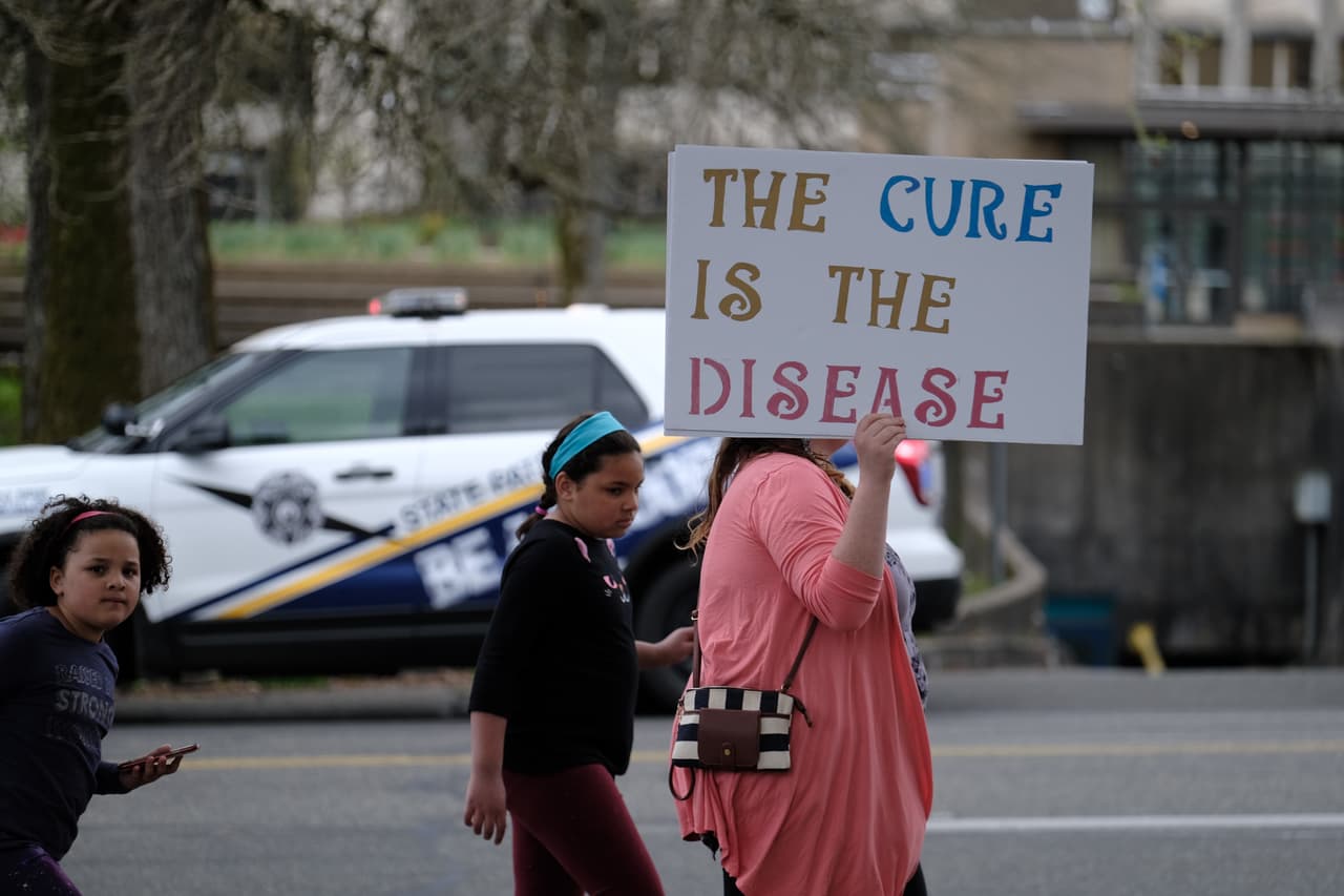<b>“La cura es la enfermedad”</b>, lee el cartel de una manifestante en Olympia, Washington, el 19 de abril. “Creo que escuchan”, añadió el presidente Trump. “Nadie quiere permanecer encerrado”.