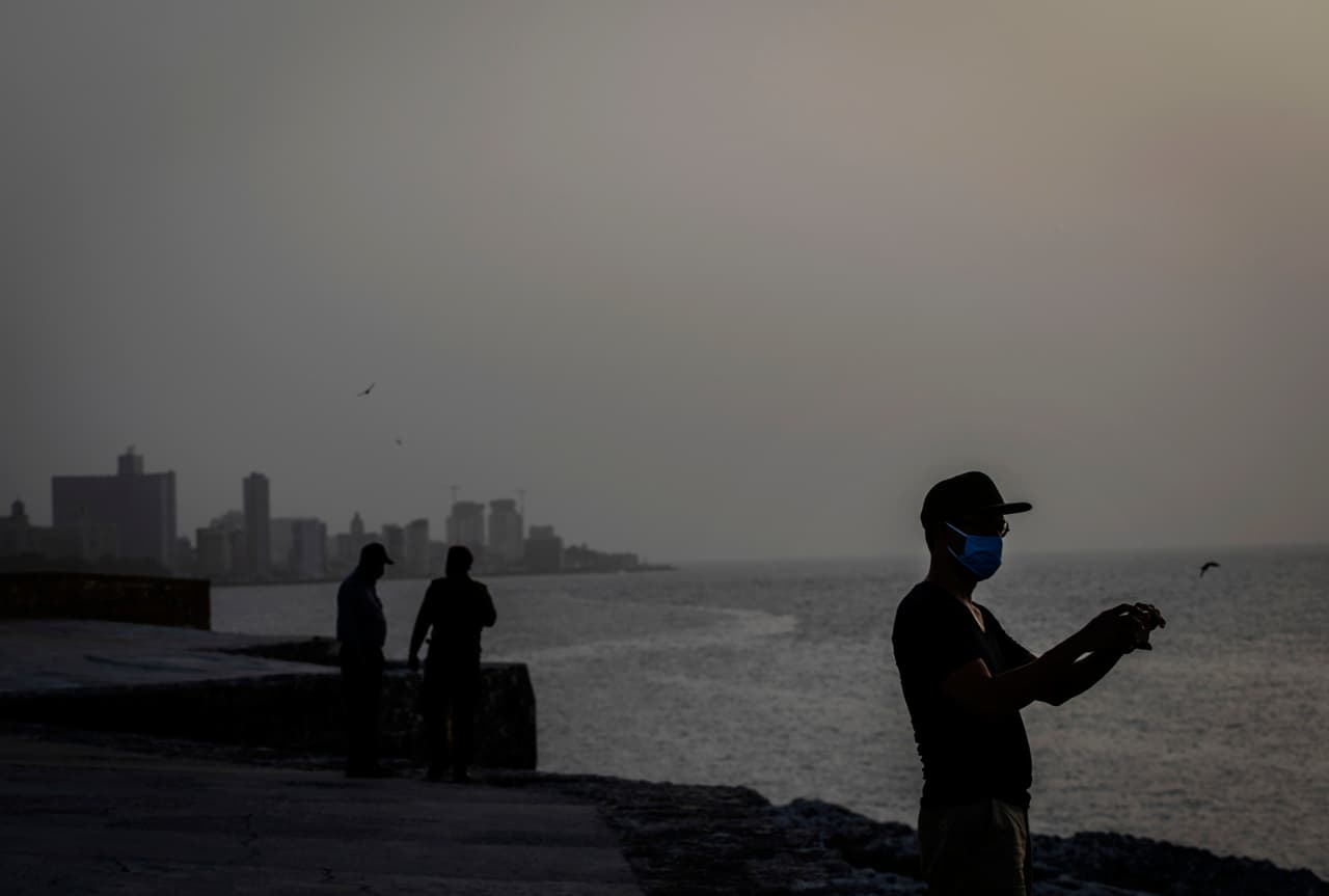 Residentes de La Habana Cuba, toman fotografías del cielo opacado por la nube de polvo del Sahara, que el 24 de junio comenzó a sobrepasar la isla. El Instituto de Meteorología cubano registró este miércoles una temperatura récord de 99.3 grados fahrenheit (37,4 centígrados) en la provincia de Guantánamo, muy cerca de la base militar de EEUU.
