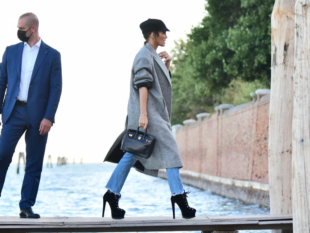 El 'outfit' de llegada lo complementó con 
<b><a href="https://www.univision.com/shows/el-gordo-y-la-flaca/quien-luce-mejor-comparamos-seis-looks-de-jennifer-lopez-y-jennifer-garner-video" target="_blank">un bolso de piel de serpiente negro</a> </b>con detalles dorados y un collar.
<br>