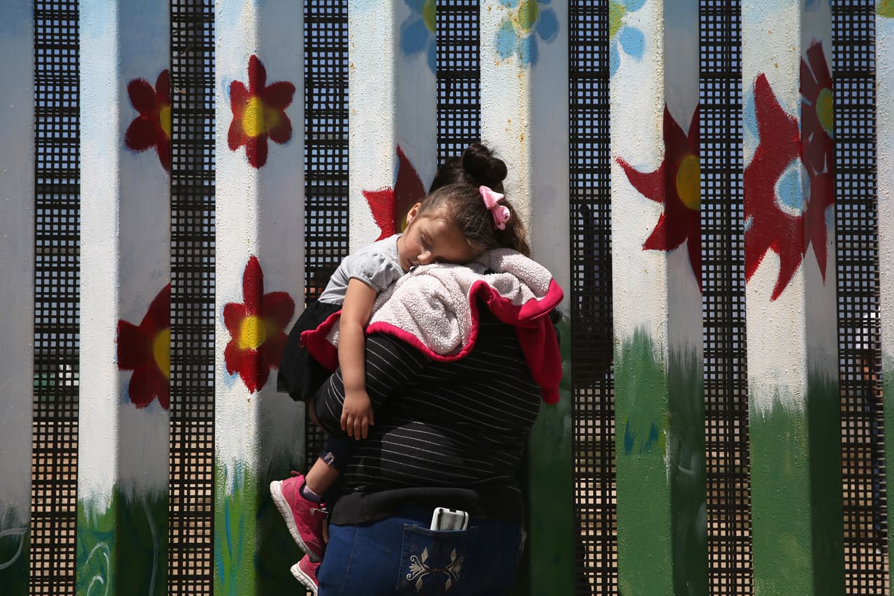 Una mujer hablar con sus familiares al otro lado de la frontera, en Tijuana