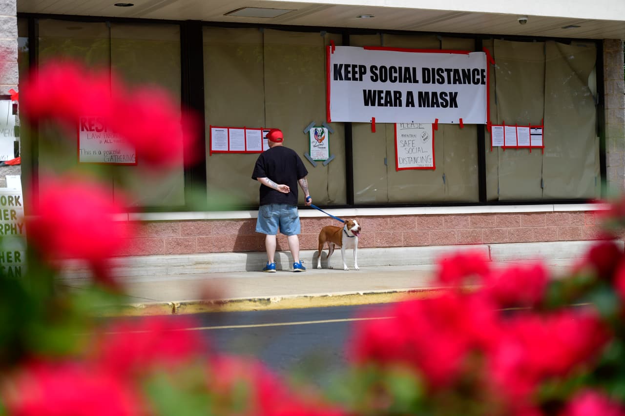 Un hombre que paseaba a su perro el miércoles lee las pancartas y los avisos fuera de gimnasio Atilis. Una de las pancartas tiene un mensaje que dice "mantega la distancia social usando una mascarilla". 
<br>Nueva Jersey está en la primera fase del plan de apertura. Los primeros negocios autorizados para abrir son construcción, venta minorista, playas, cines al aire libre desde el auto y servicios religiosos que deben operar con limitaciones.