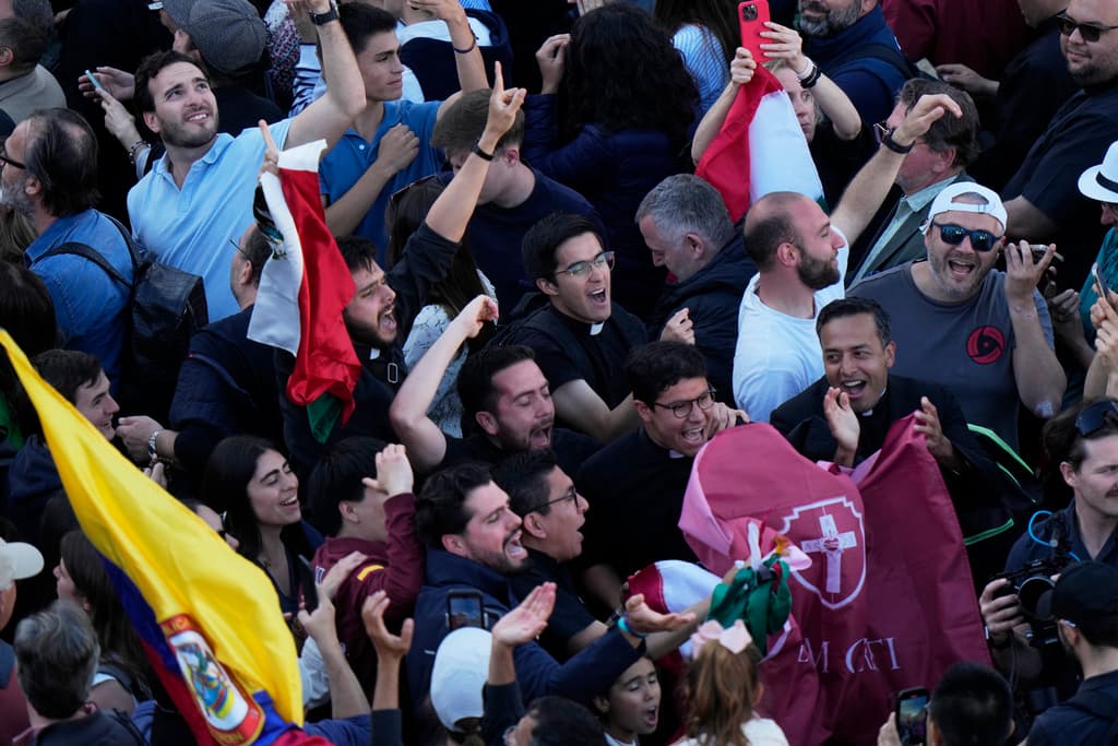 La gente reacciona ante columnas de humo blanco que salen de la chimenea de la Capilla Sixtina, donde 133 cardenales se reúnen en el segundo día del cónclave para elegir al sucesor del difunto Papa Francisco, en el Vaticano, el jueves 8 de mayo de 2025. (Foto AP/Luca Bruno)