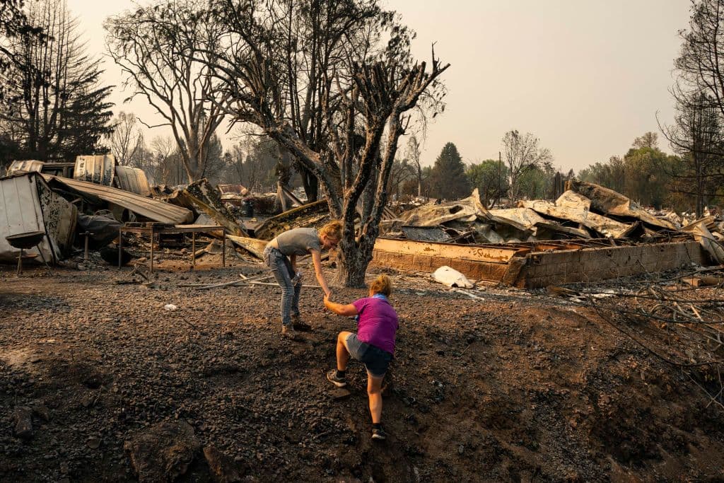 Amie Emery (a la derecha) y su hija Erin Emery camino a ver qué quedó de la casa de su suegra en el parque de casas rodantes en Phoenix, Oregon, después del azote del incendio. Jairo Gómez, que vivía en esa comunidad, dijo al diario 
<i>The Washington Post</i>, que el incendio fue "muy grande" y que "en menos de cinco minutos, todo había desaparecido".