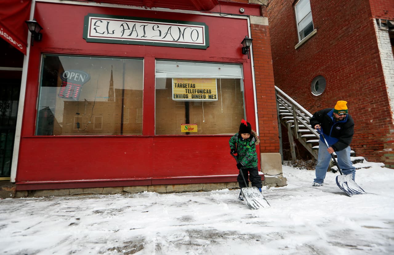 Danny Jiménez, a la izquierda, de 7 años, ayuda a su padre, Luis, a limpiar la nieve de la acera a lo largo de la avenida Central, en Dubuque, Iowa.